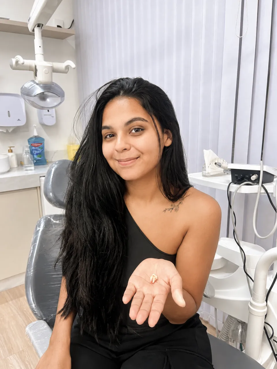 Paciente sorrindo na cadeira odontológica após extração de dente