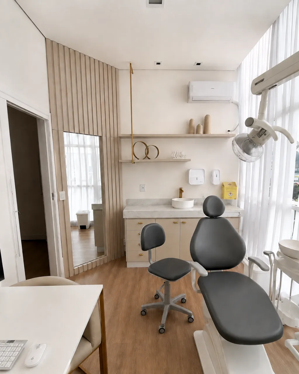 Sala clínica com cadeira odontológica, bancada de mármore e luz natural
